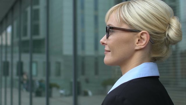 Female business person standing near office center and looking aside, confidence