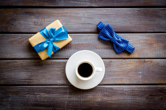 Greeting card for men's birthday. Present box, bow tie and coffee on dark wooden background top view