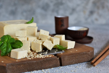 Soy cheese - classic tofu cheese on a wooden board on the kitchen table.