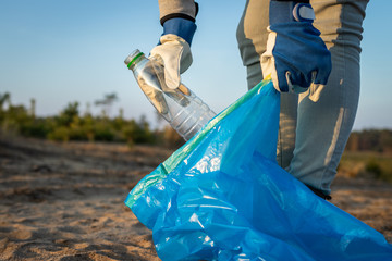 Plastic pollution. Activist cleaning beach from plastic waste. Environmental cleanup