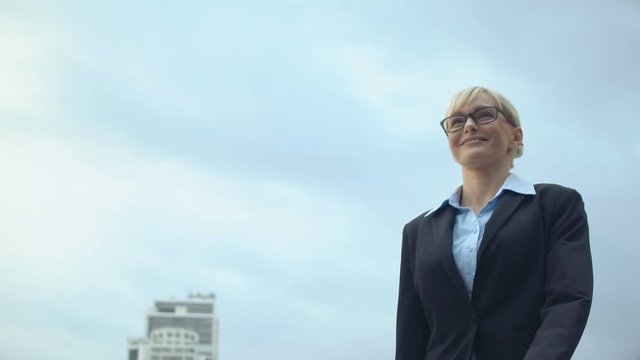 Smiling woman in formalwear walking on sky background, career promotion, success