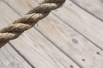 Obraz premium Aged rope with wooden floor boards in the background creating a natural aged texture for use as a background.