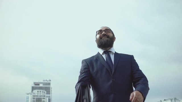 Successful businessman throwing handbag and making winner gesture, inspiration