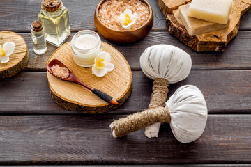 Massage thai herbal balls near spa accessories on dark wooden background