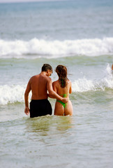 young couple wading in shallow water at beach