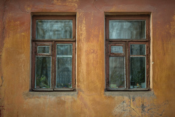 Two windows on the facade of an old stone house.
