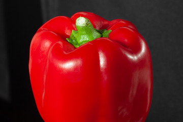 Juicy red pepper on black background