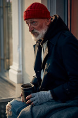 Senior caucasian homeless man sit begging for money. Nothing to live for. Dressed in street clothes.