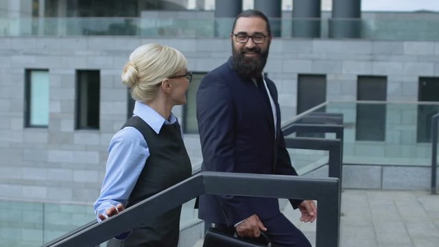 Business partners approaching modern office center walking upstairs and talking