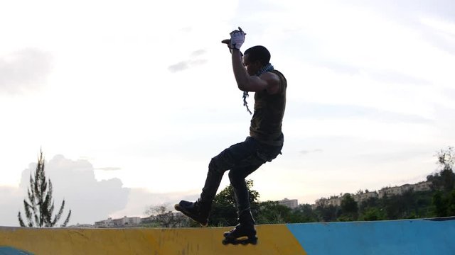 Low angle shot of a professional young boy jumping on the ramp with rollerblades 