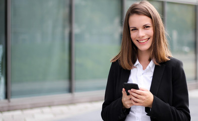 Smiling businesswoman using a smartphone outdoor