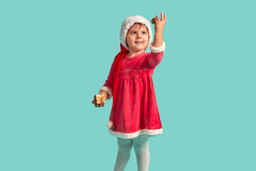 Adorable small baby girl in christmas hat and red dress on the studio background