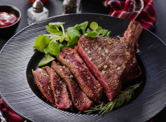 Steak on the bone. Rib eye. Tomahawk steak on the black plate with rosemary. Roasting - Rare. Entrecote