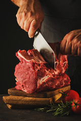 Male butcher cuts raw beef meat.