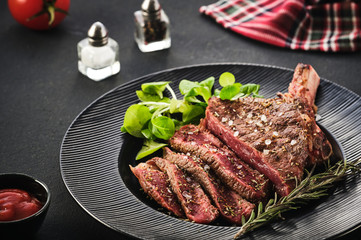 Steak on the bone. Rib eye. Tomahawk steak on the black plate with rosemary. Roasting - Rare. Entrecote