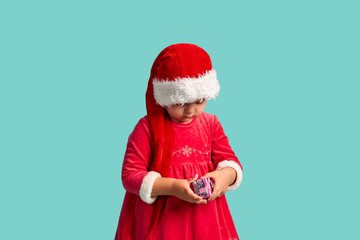 Fototapeta na wymiar Adorable small baby girl in christmas hat and red dress on the studio background