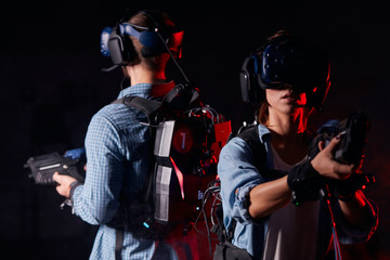 Neon backlit background. Isolated. Two young people stand back to back, together fighting with fictional enemy