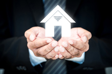 Fototapeta na wymiar Businessman hand holding a model home presenting in the office, Saving money for buy a new house or loan for plan business investment of real estate concept.