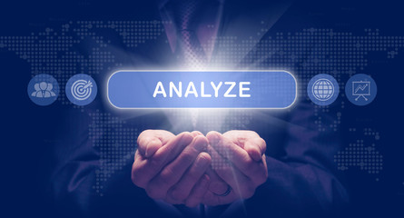 Businessmans cupped hands holding a Analyze business concept on a computerised display.