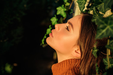 Profile portrait of beautiful model with natural make up and perfect smooth skin catching the last sunshine light. Autumn queen. Close up portrait of sexy brunette woman.