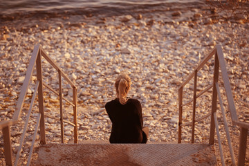 the girl sits on the nature by the sea and looks into the distance