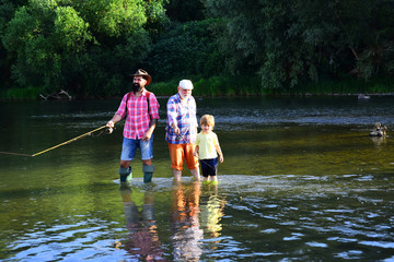 Senior man fishing with son and grandson. Grandpa and grandson are fly fishing on river. Men hobby....