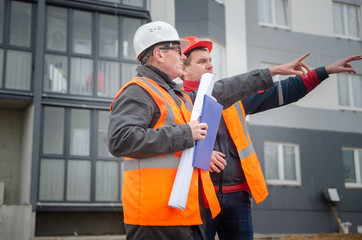 An engineer with a hard hat and helmet discussing a project at a construction site with a team leader. architecture construction concept. Industrial safety