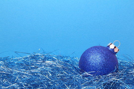 Christmas Card With Blue Tinsel And Blue Glitter Ball On Blue Background