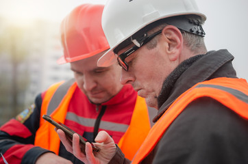 An engineer with a hard hat and helmet discussing a project at a construction site with a team...