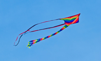 A beautiful, colourful stunt kite, in the blue sky, high up in the wind