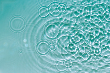 Water abstract background with blue rippled aqua texture, splash circle reflections in swimming pool. Top view