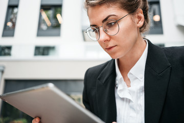Fototapeta premium Portrait of pensive business lady wearing eye glasses using personal digital tablet for project social media. Close-up female creative designer with digital pad
