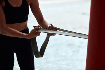 Cropped fit female in sportive topic pulling rope in gym. Window background