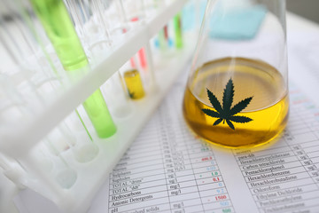 Test tube with yellow cbd oil in chemistry lab closeup