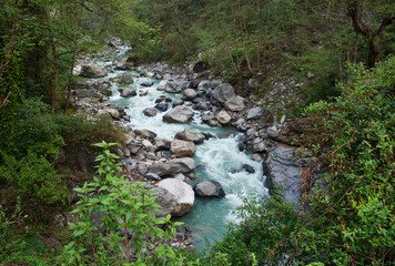 Beautiful landscape with a stormy mountain river of blue color in the jungle of Nepal, on a cloudy day.