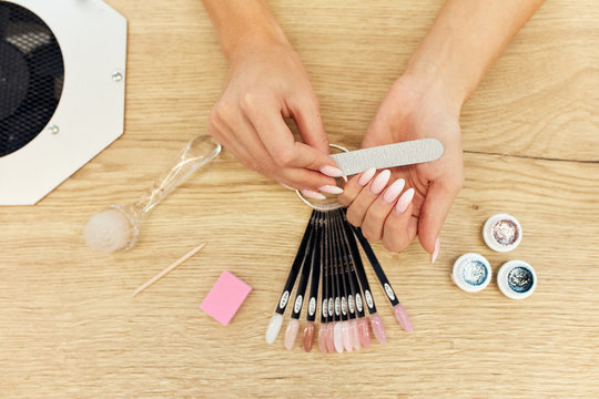 Nail file, nail colors on wooden table. Beautiful hands cut nails, polishing