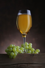 Glass of white wine with grape on wooden table