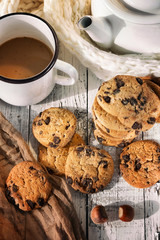 Coffee with milk in a white mug. Near a white teapot and scattered cookies with chocolate
