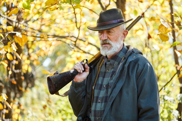 Forest hunting on animals. Senior man holding shotgun, Upset after hunting in forest
