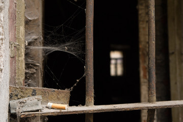 the cigarette butt lies on the bars of the dark window