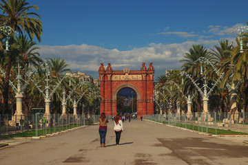 Turistas en el Arco del triunfo en Barcelona rodeado de palmeras