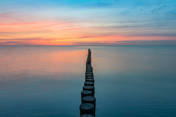 Baltic sea seascape at sunset, Poland, wooden breakwater and waves