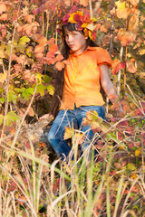 The Autumn Girl. Girl in a wreath of yellow leaves sits on a background of autumn foliage