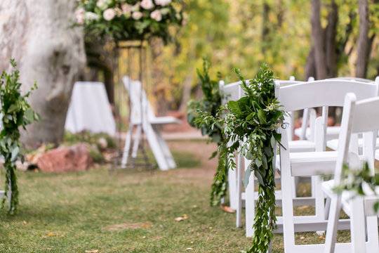 green decor on white chairs for wedding ceremony