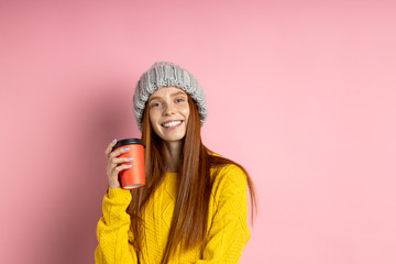 Redhead woman holding disposable cup of coffee
