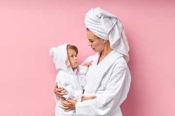 After taking bath, mother and her daughter in bathrobe and towel.isolated pink background
