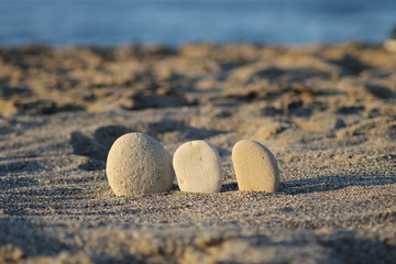 Fototapeta na wymiar Three pebbles in a row on the sunset beach.