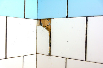 White and blue tiles on the wall. Old and broken tiles require replacement. Abstract background.