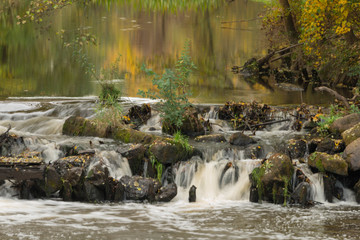 Obraz premium Wodospad na rzece płynącej przez las.