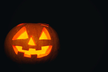 Glowing scary Halloween Pumpkin lantern on black background.